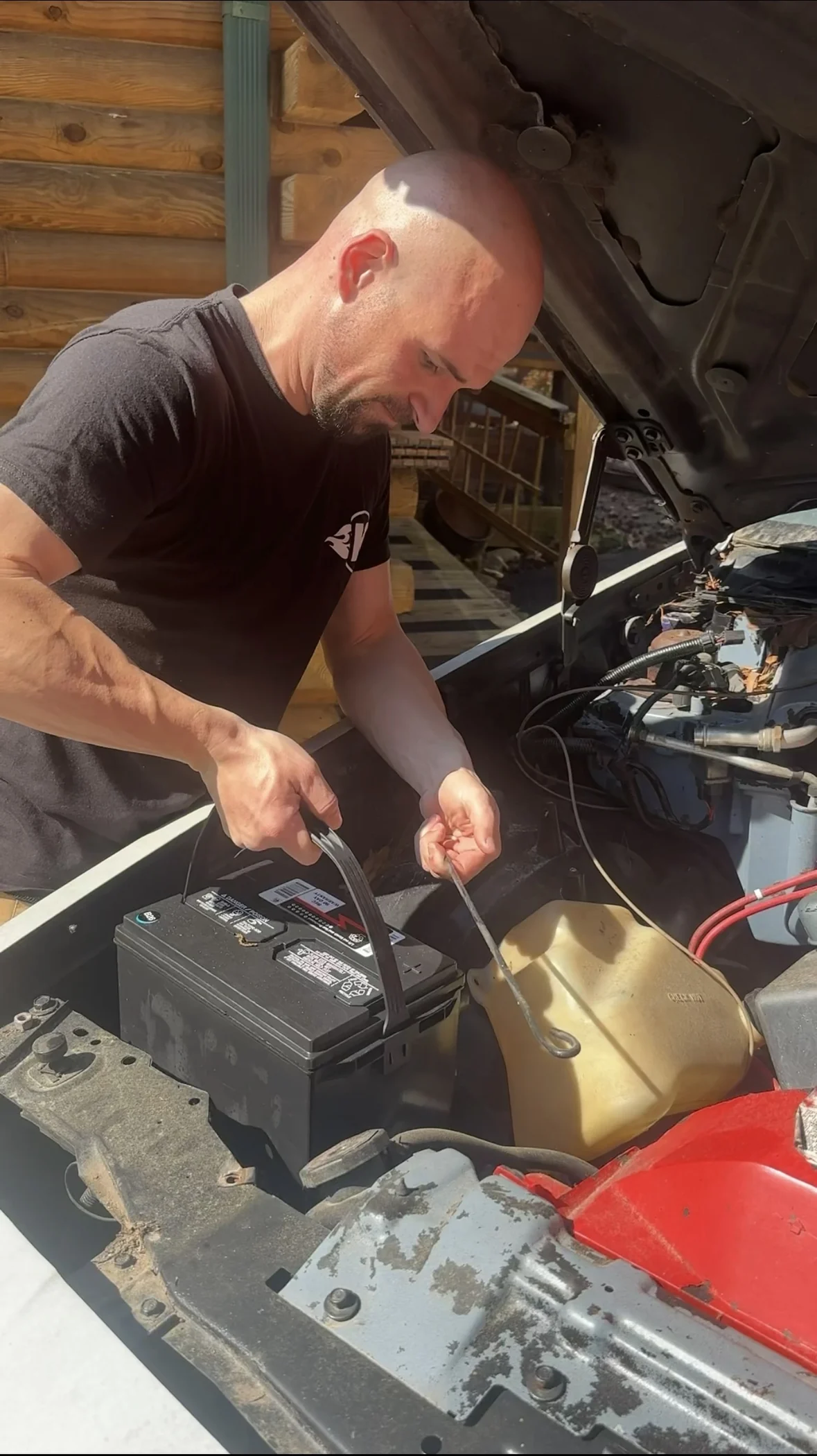 Cory working under the open hood of a project car